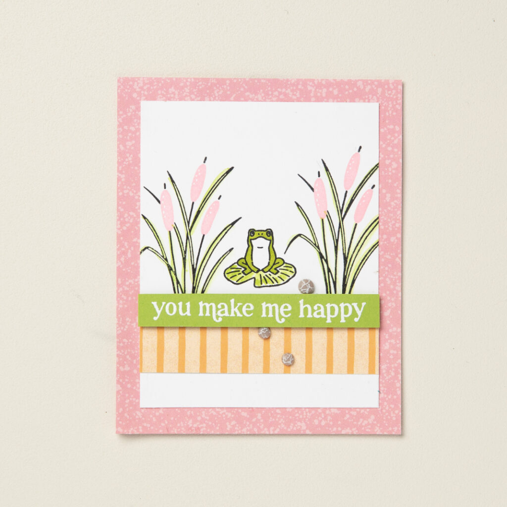 A cute handmade card featuring a frog on a lily pad.