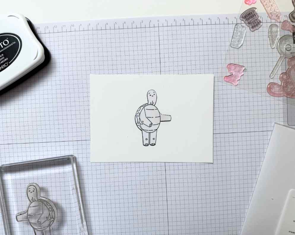 Ink is applied to exposed cardstock areas while the stamped image remains protected by masking paper.