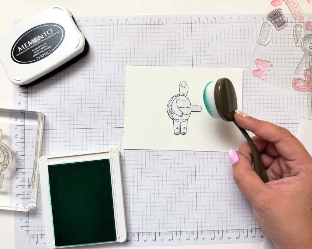 A card making workspace shows ink pads, stamps, and masking paper set up for creating clean color-blocked designs