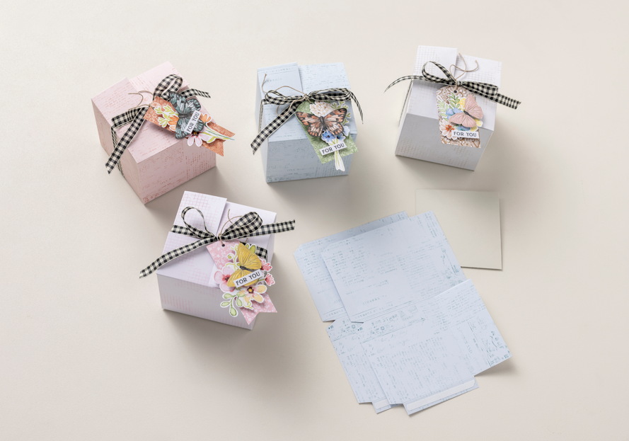 Doe-het-zelf geschenkdozen van wenskaarten met pastelkleurig kaartkarton, vlinderdecoraties en strikjes van zwart ruitjeslint.
