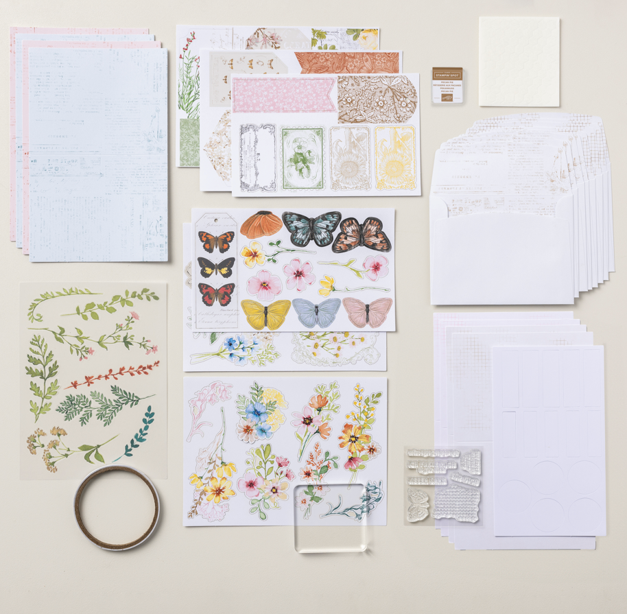 Materiaal om een geschenkdoos te maken van een wenskaart, inclusief bedrukte voorgestanste motieven, bloemen- en vlinderstansfiguren, stempels, lijm en kaartkarton.