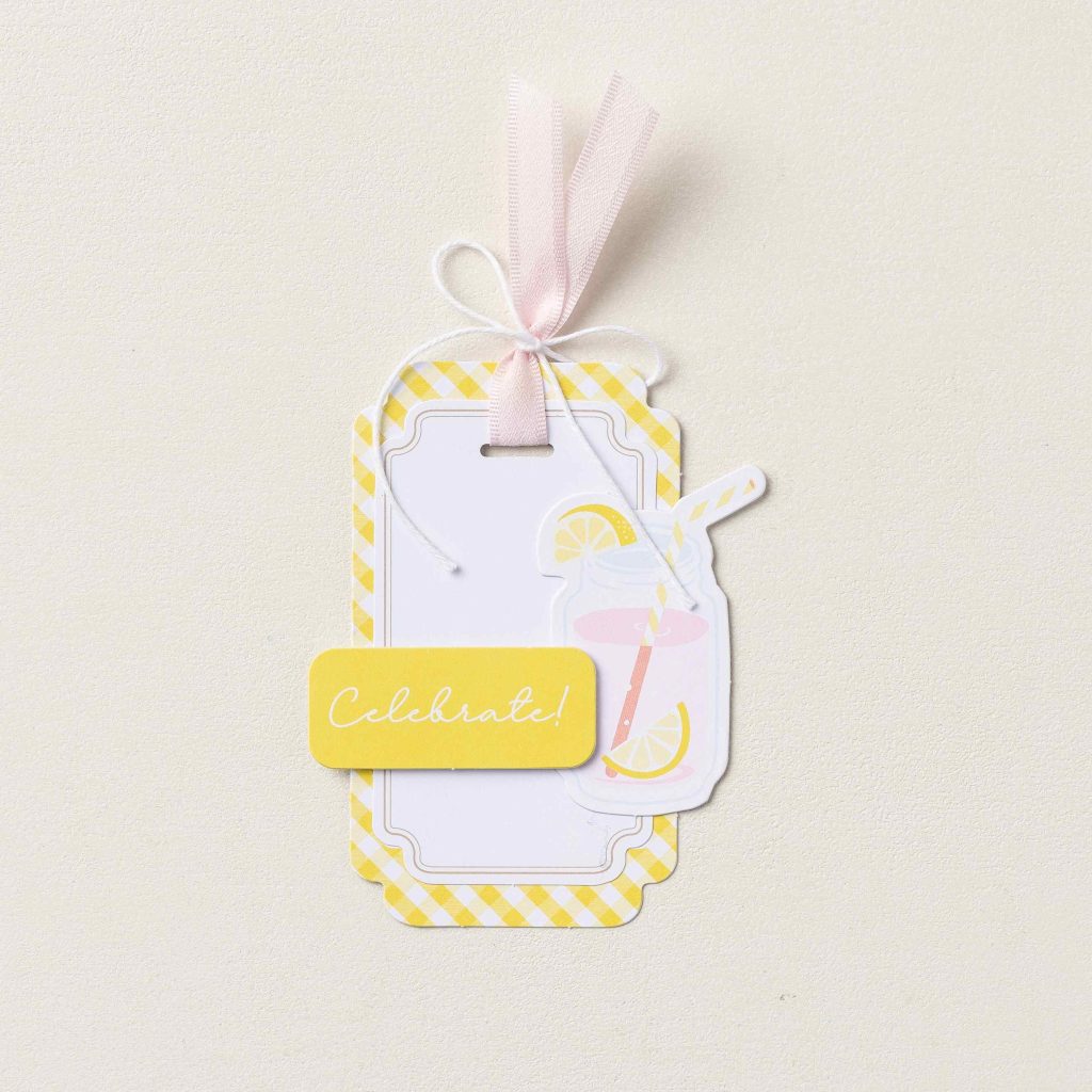 Handmade gift tag decorated with Barely Blush ribbon tied into a bow and layered paper embellishments for gift giving.