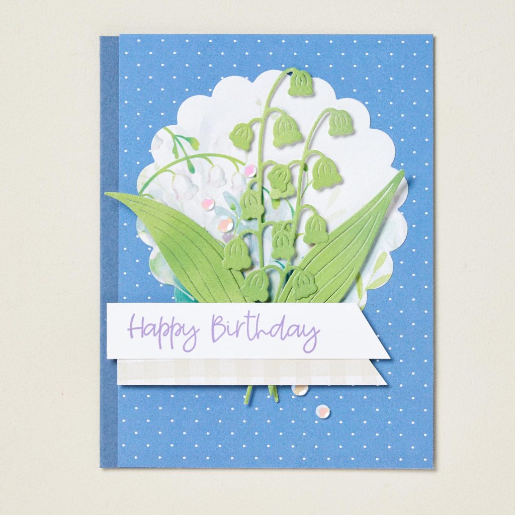 Handmade floral birthday card featuring layered lily of the valley flowers on a blue polka dot background.