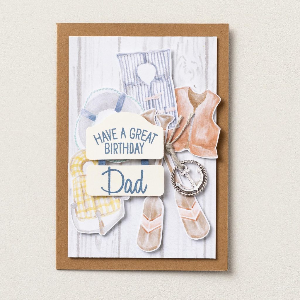Handmade birthday card for Dad featuring lakeside essentials including a life jacket, inner tube, towel, anchor charm, and "Have a Great Birthday Dad" greeting.