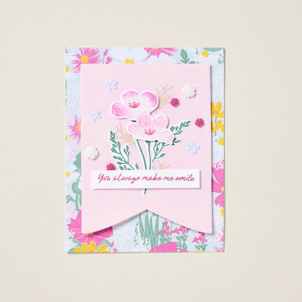 Pink floral handmade greeting card decorated with layered flower embellishments, patterned paper, and dimensional accents.