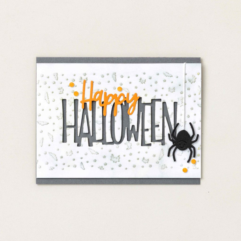 Carte d'Halloween faite main, ornée d'une inscription « Happy Halloween » en caractères gras et d'une araignée noire sur un fond blanc épuré.
