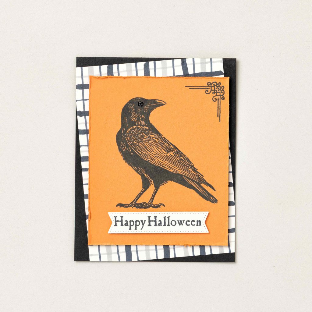 Carte d'Halloween faite main, ornée d'une illustration vintage représentant un corbeau sur du papier cartonné orange, avec une inscription « Happy Halloween ».