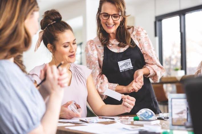 A Stampin’ Up! demonstrator helping a group of crafters create handmade paper projects together during a crafting class.