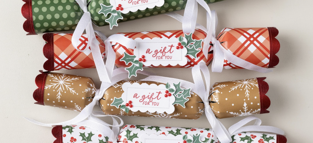 Des médailles de Noël en papier festif avec des rubans blancs et des plaques festonnées « un cadeau pour vous » décorées de houx et de baies rouges.