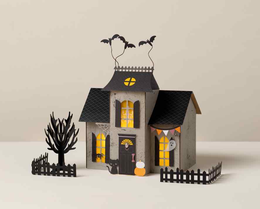 DIY paper haunted house with bats, glowing windows, pumpkins, tree, and picket fence