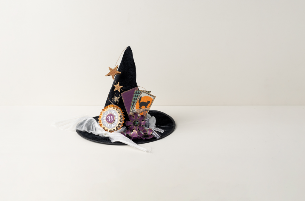 Klaargemaakte DIY-Halloween-heksenhoed, versierd met een zwarte kat, sterren, bloemen, een spin en motieven die verwijzen naar 31 oktober