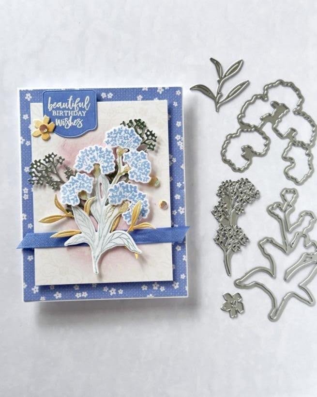 Handmade birthday card featuring layered blue flowers, floral die cuts, and blue ribbon