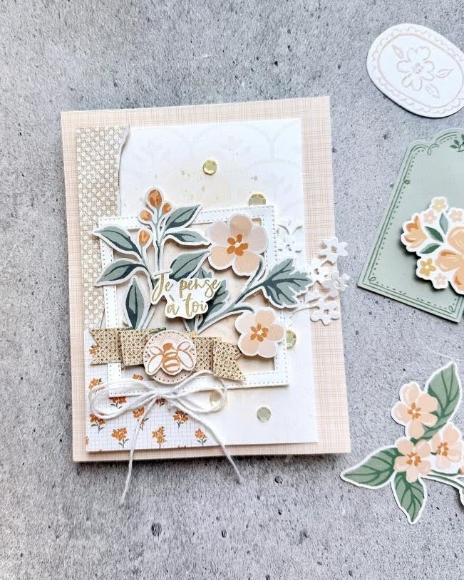 Layered handmade card with peach flowers, greenery, bee embellishment, and a white twine bow