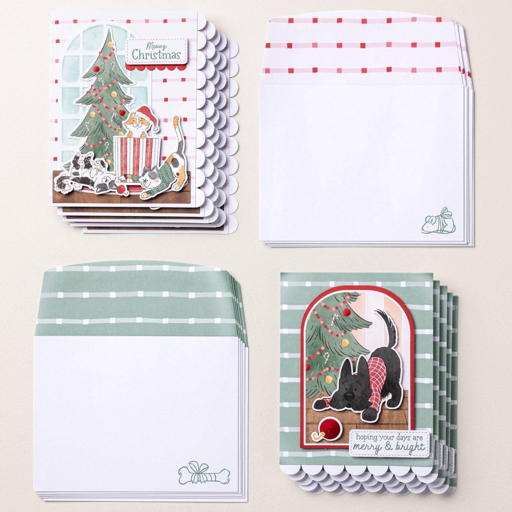 Des lots de cartes de Noël et d'enveloppes faites à la main, représentant des chats et des chiens aux côtés de sapins de Noël décorés.