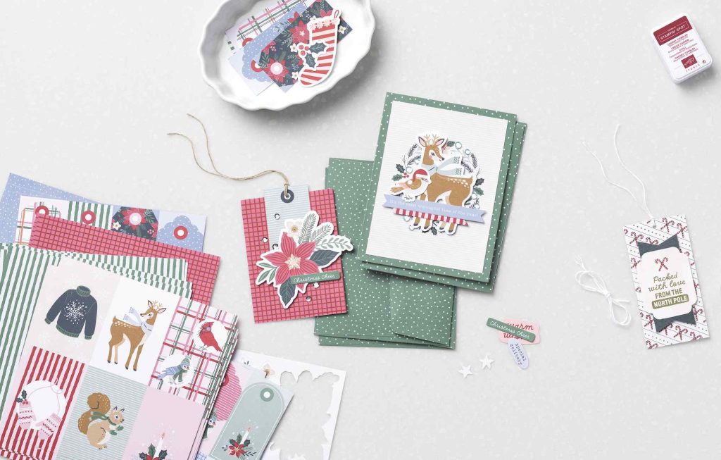 Présentoir suspendu comprenant du papier de Noël, des éléments décoratifs, une carte représentant un renne, des étiquettes en forme de poinsettia et de canne à sucre, de la ficelle et un tampon encreur.