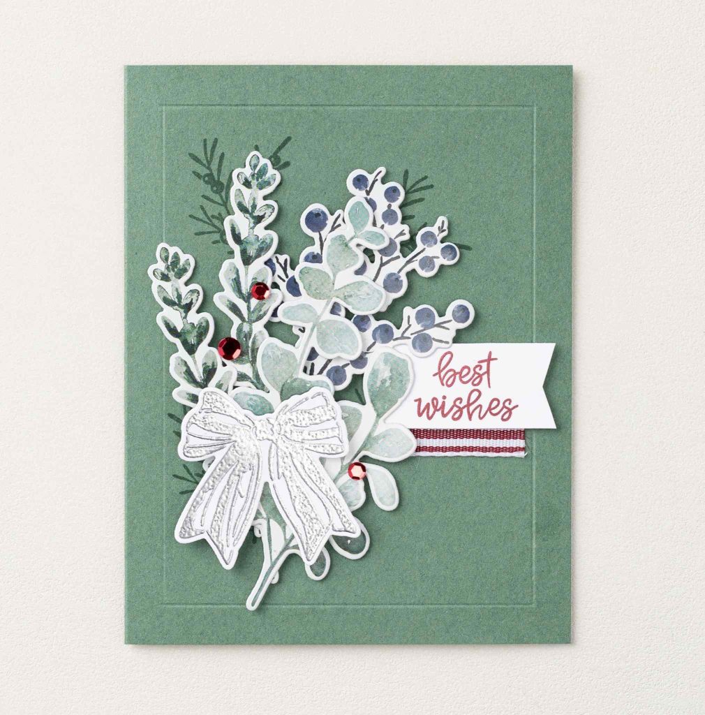 Green card with layered aqua leaves, blue berries, a silver bow, red gems, and a white banner reading “Best Wishes.”