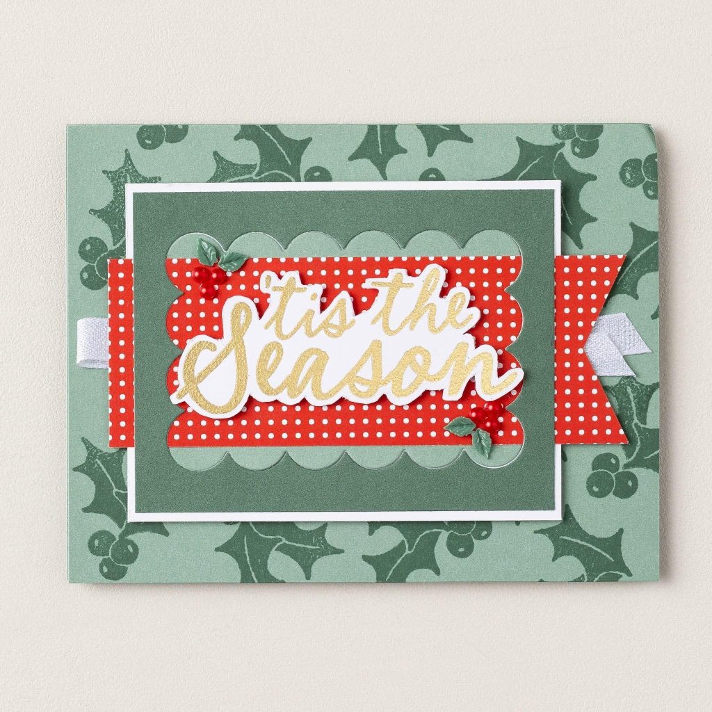 Carte de Noël faite main avec un fond vert de houx, du papier à pois rouges, un ruban blanc et l'inscription « Tis the Season » en lettres d'or.