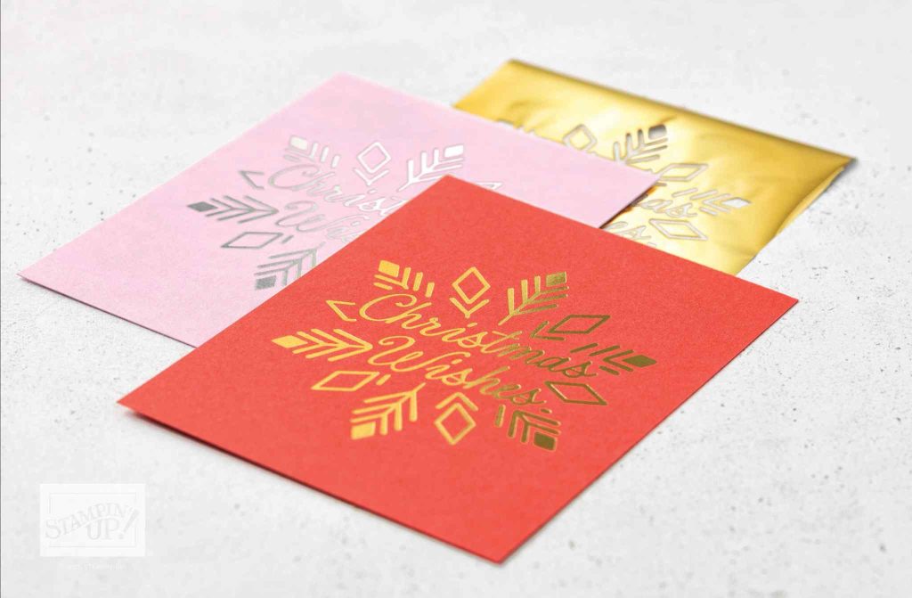 Overlapping red, pink, and metallic gold card panels decorated with metallic snowflake designs and script reading “Christmas Wishes.”