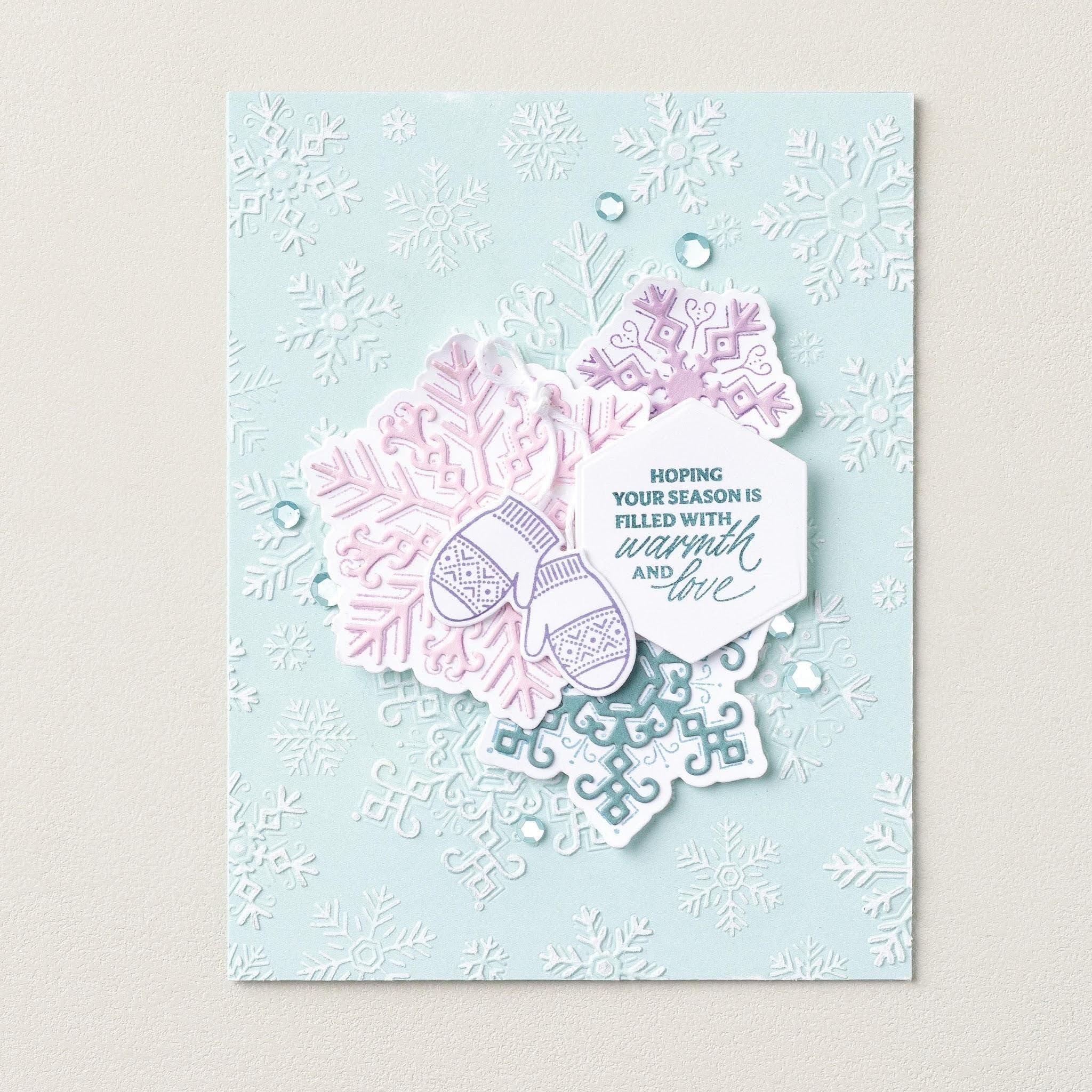 Carte couleur aqua pâle ornée de flocons de neige en relief, de flocons de neige superposés roses et violets, de mitaines, de paillettes et d'un message d'amour et de chaleur.